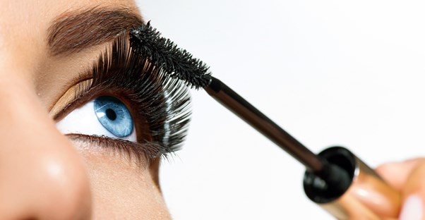 Close up of blued woman applying mascara to her lashes after extending the life of her mascara.