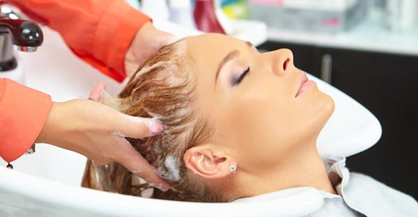 Woman having her hair washed with anti-frizz shampoo