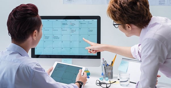 Two people looking at calendar on computer screen