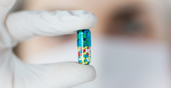 Woman with a background in science holding a pill