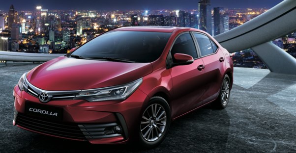 a 2018 red toyota corolla in front of a city skyline