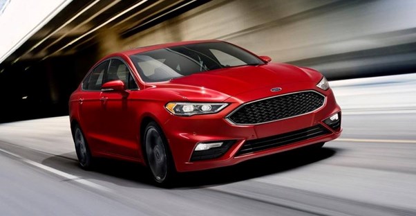 a red 2018 ford fusion driving down the street