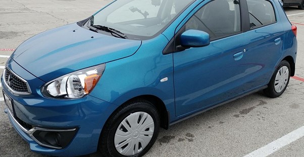 a blue mitsubishi mirage sits in a parking lot