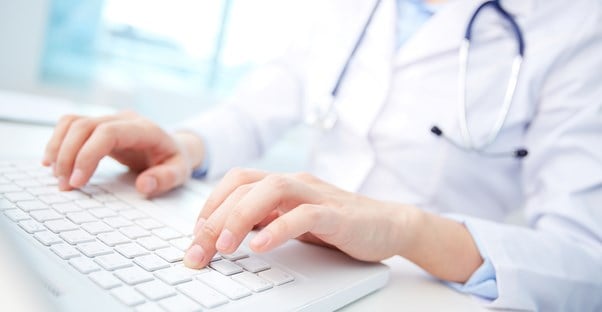 a medical transcriptionist typing up a report on a computer