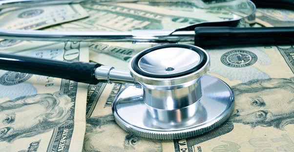 A stethoscope sitting on top of the money from a nurse practitioners salary.