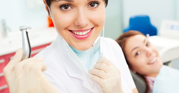 A dental hygienist and her patient take a break from surgery to smile at the camera