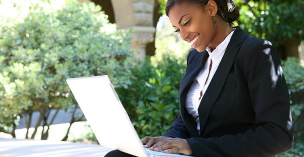 A woman smiles as she works on her laptop