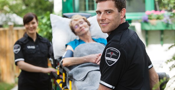 EMTs smile as they take an injured woman to the hospital on a stretcher