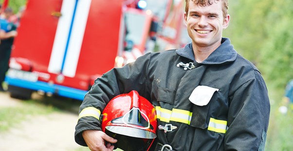 Firefighter poses with his helmet and smiles