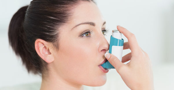 a woman uses an inhaler for her asthma symptoms