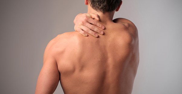 a man holds his shoulder because of his back pain
