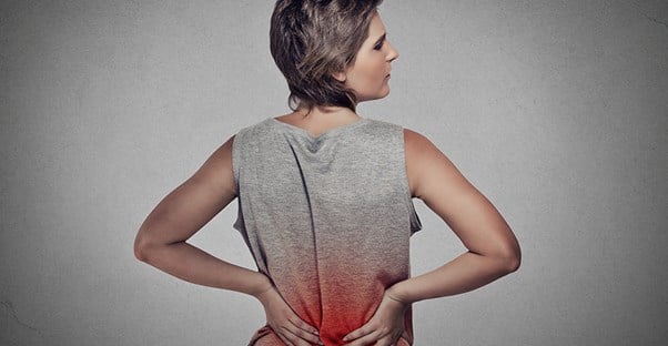 Woman in gray shirt experiencing back pain