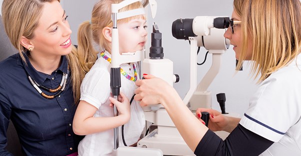 child being examined by the eye doctor because she has symptoms of strabismus