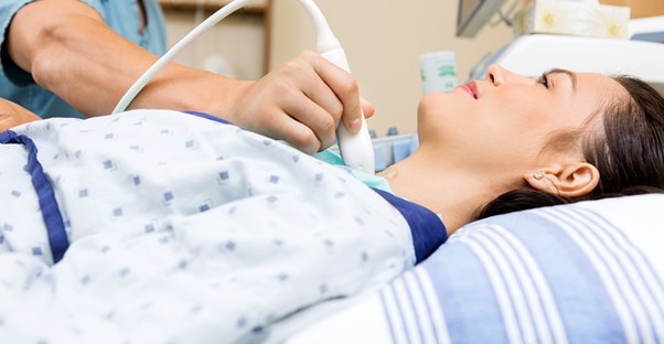 a patient lying down having her throat examined using an ultrasound