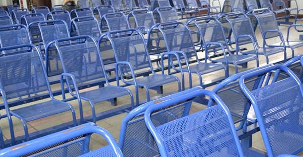 An array of empty blue chairs wait for patients to sit in them.