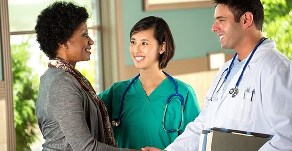 two health professionals greet a patient