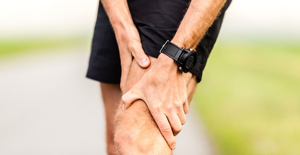 a runner grasps an area of knee pain