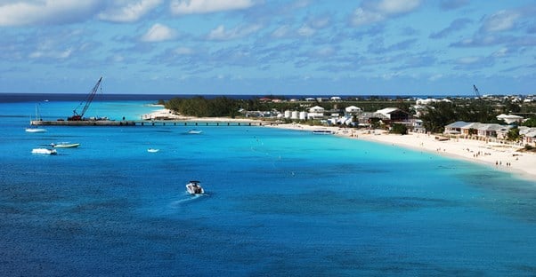 a view of a Turks and Caicos harbor with people on the beach and boats in the ocean
