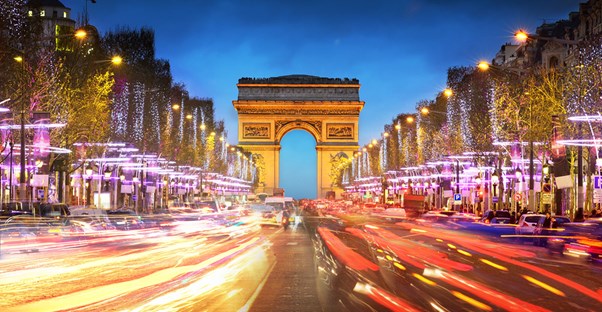 the arc de triomphe is light up colorfully at night
