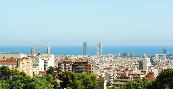 the barcelona skyline extends to the ocean on a sunny day