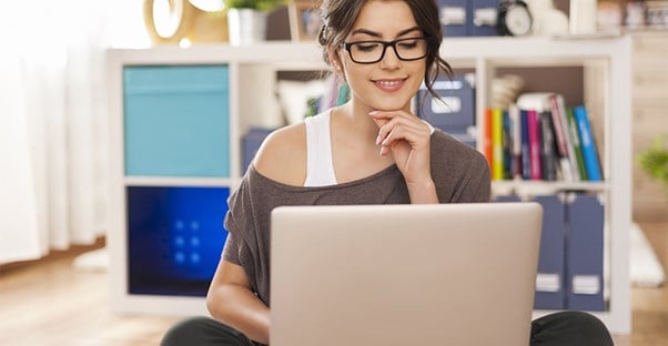 Smiling woman wearing glasses looking at a laptop screen