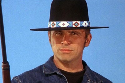 a man wearing a cowboy hat in front of a blue sky