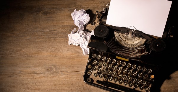 Typewriter with crumpled pieces of paper lying beside it
