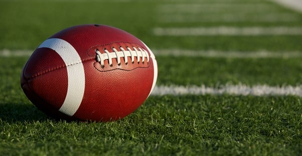 A football laying on a football field.