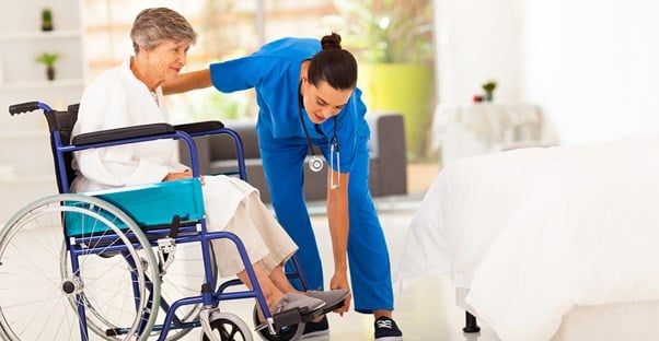An elderly woman being assisted at a senior care center.