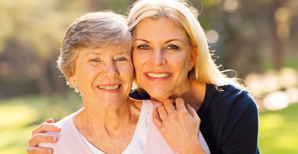 Woman and her ill mother smile, enjoying the time they spend together with at home care