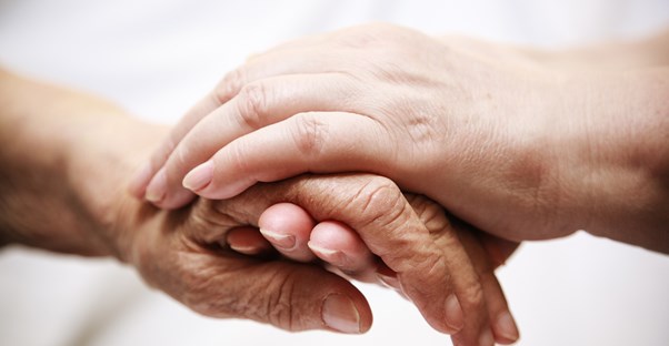Clasped hands belonging to an elderly man and his daughter as they discuss senior care.