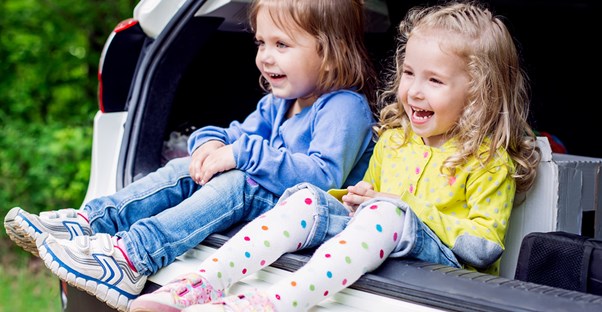 Two little girls smile when they hear the healthy snacks they will eat on a road trip