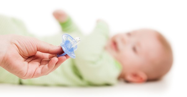 A mom holding the pacifier that caused her baby's pacifier rash.