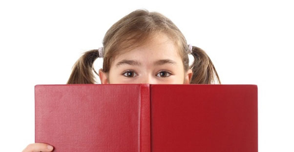 A young girl reads a red book
