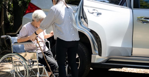 A senior being helped into a car