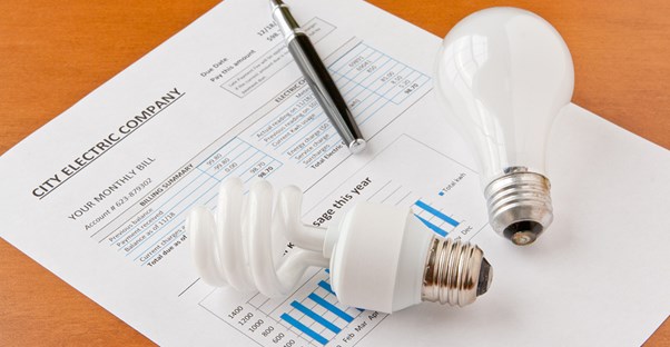 a cfl and incadescent light bulb lying on an electricity bill