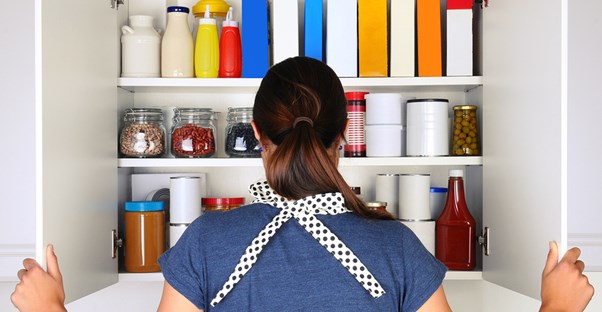 a woman gazes into her immaculately organized kitchen pantry