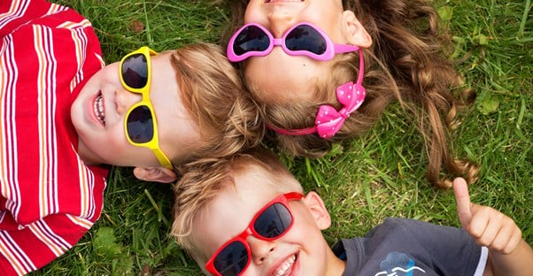 stylish kids lie in the grass with cool sunglasses on