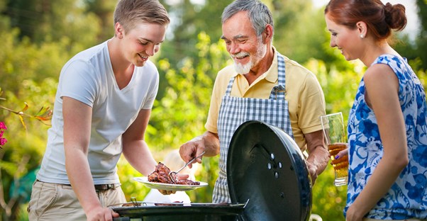 A father discuss the pros and cons of charcoal and gas grills with his hungry children