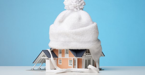 A cute white hat keeps a toy house warm and cozy