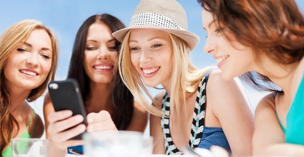 A group of friends look at a photo book app on a smart phone