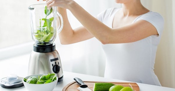 Woman making a green smoothie for her vegan diet