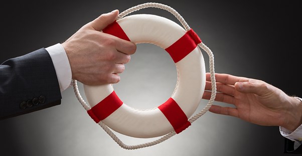 One hand with a small red and white lifesaver from a boat handing it off to someone else to represent how life insurance changes with age