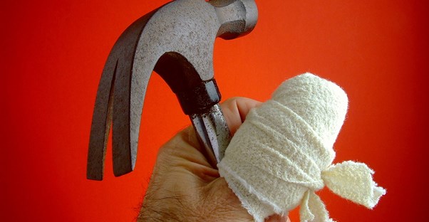 Man holding a hammer with an injured thumb wrapped up