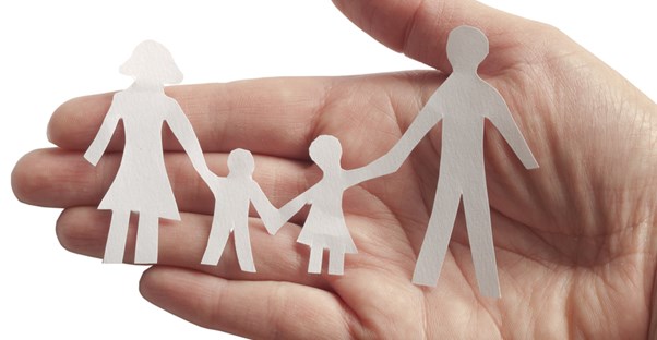 A hand holding paper cut outs of a family as a visual representation of feeling your health insurance will take care of your family medical needs.