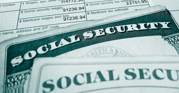 Social security cards lying on top of a paycheck stub outlining how much money went to the social security tax.