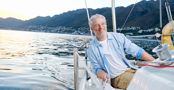 A retired gentlemen smiling on his boat because he understands the basics of social security retirement benefits.