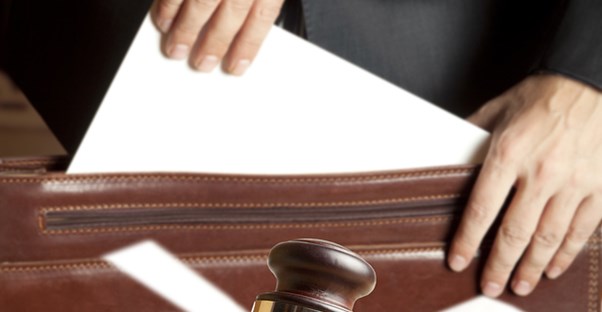 Lawyer removing a paper from a briefcase in front of a judge