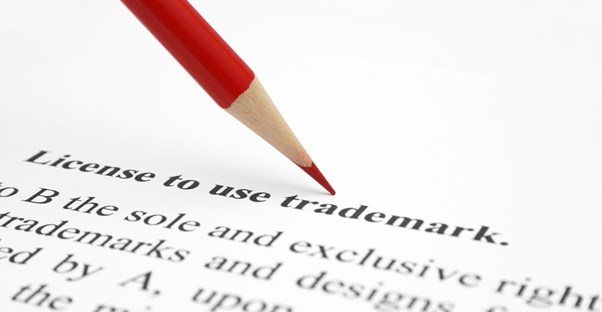 legal document with zoomed in focus on the word trademark, pointed to by a red pencil