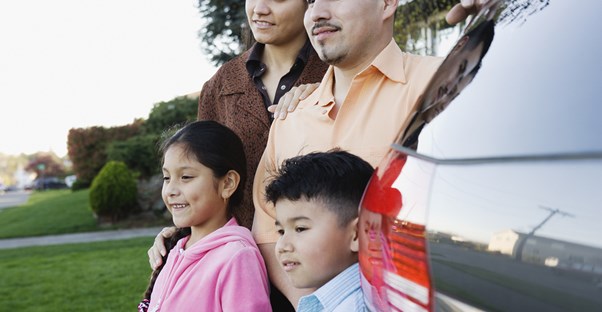 Family standing next to a minivan